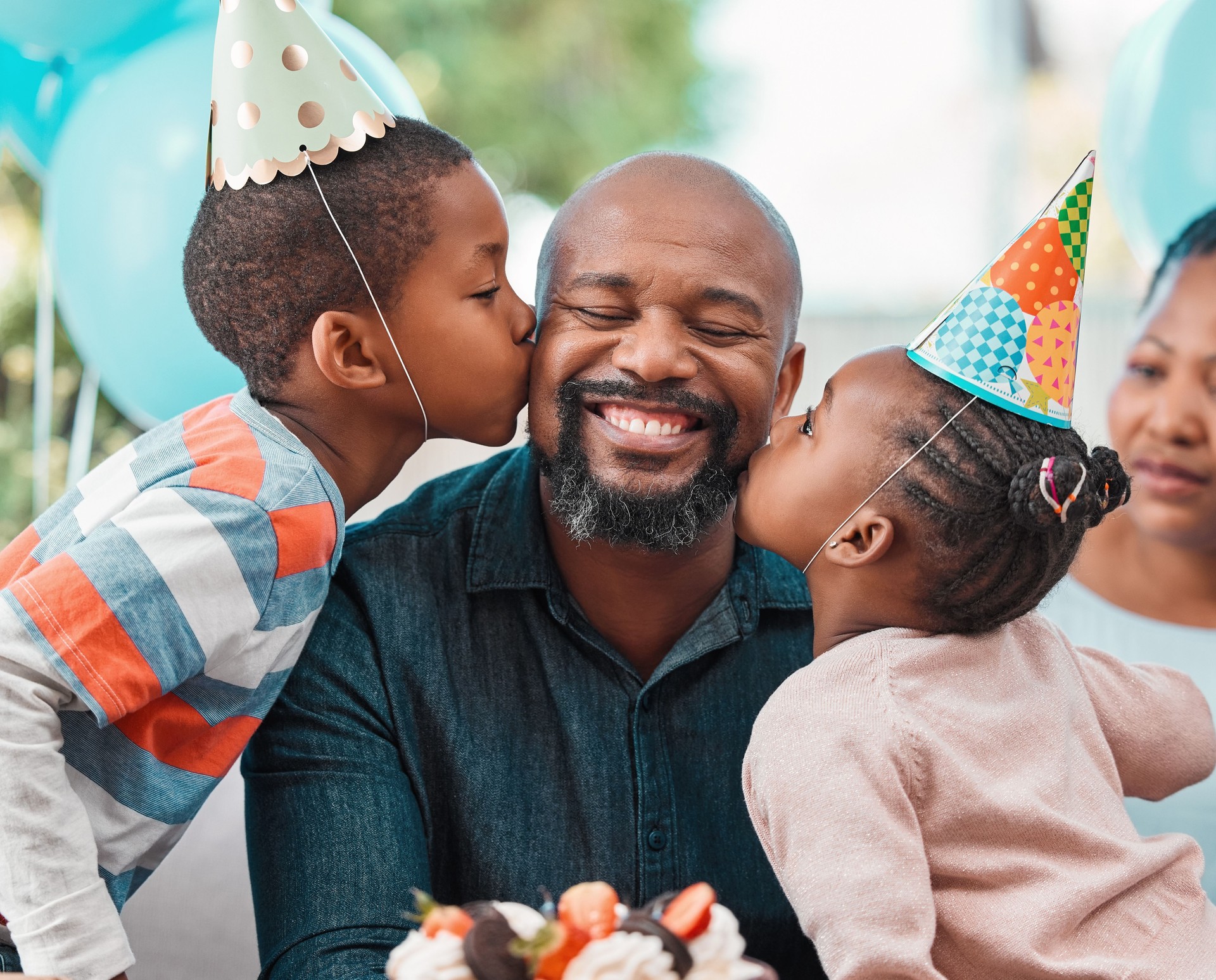 Photo de deux enfants embrassant un homme mûr sur ses joues lors d’une fête d’anniversaire
